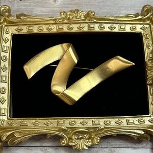 Vintage Monet gold-tone ribbon-shaped brooch with a modernist design